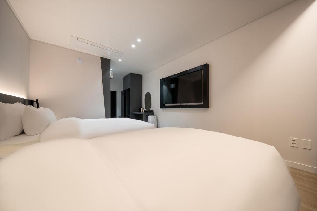 a bedroom with two white beds and a flat screen tv at Hound Hotel Mokpo Peace Plaza in Mokpo