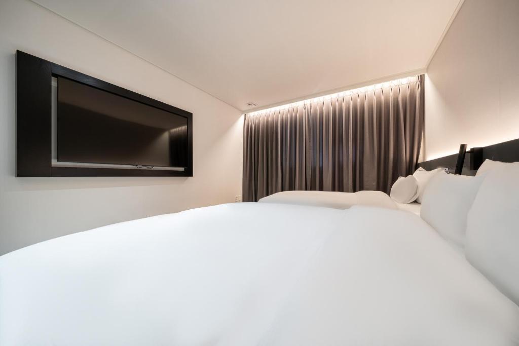 a hotel room with two beds and a flat screen tv at Hound Hotel Mokpo Peace Plaza in Mokpo