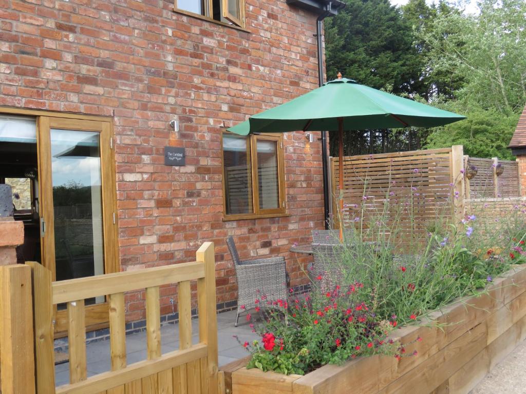 a patio with a green umbrella and a wooden fence at The Cartshed in Worcester