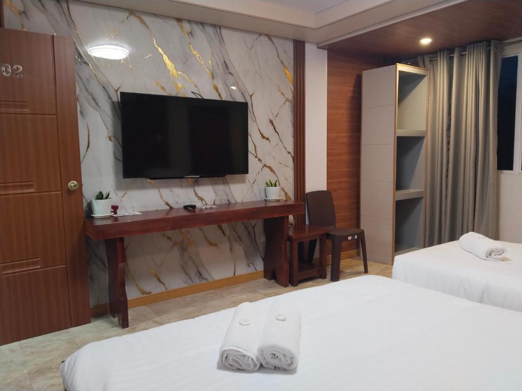 Una habitación de hotel con dos camas y un escritorio con televisión. en Gibraltar Inn, en Baguio