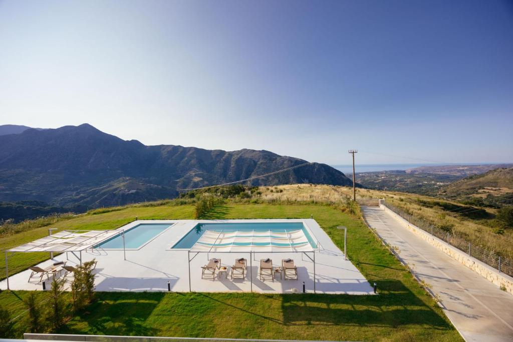a house with a swimming pool on a hill with a road at Mountain Dream Panorama in Aryiroúpolis
