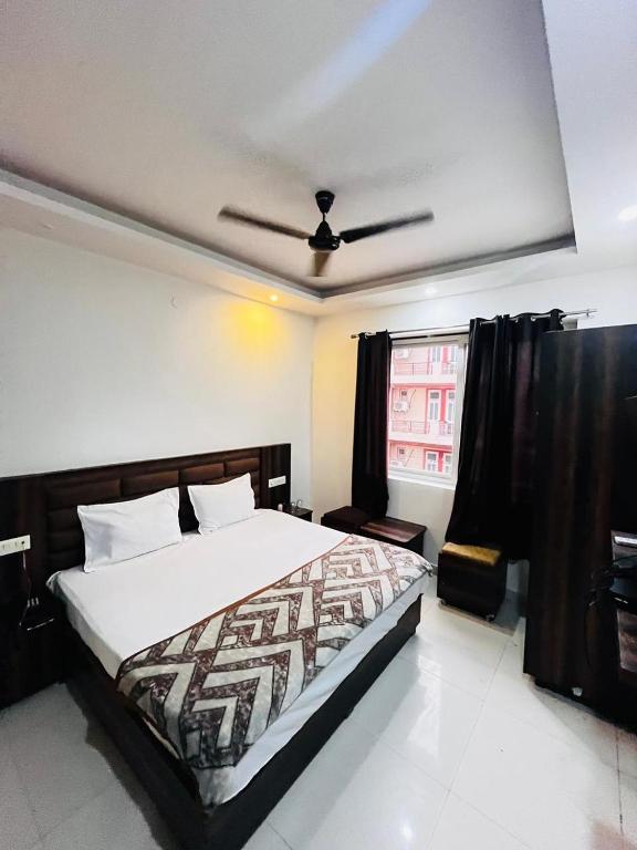 a bedroom with a large bed and a window at Hotel Wisteria Haridwar in Haridwār