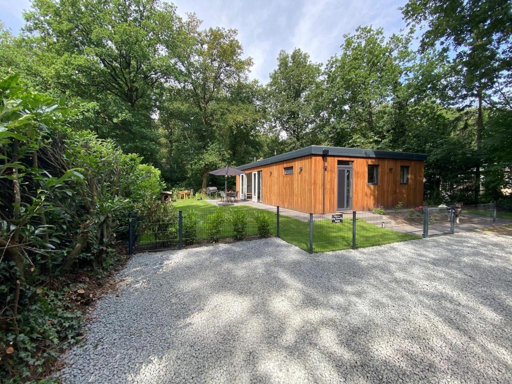 a small wooden cabin with a fence in a yard at Luxury bungalow Woldzicht in Appelscha