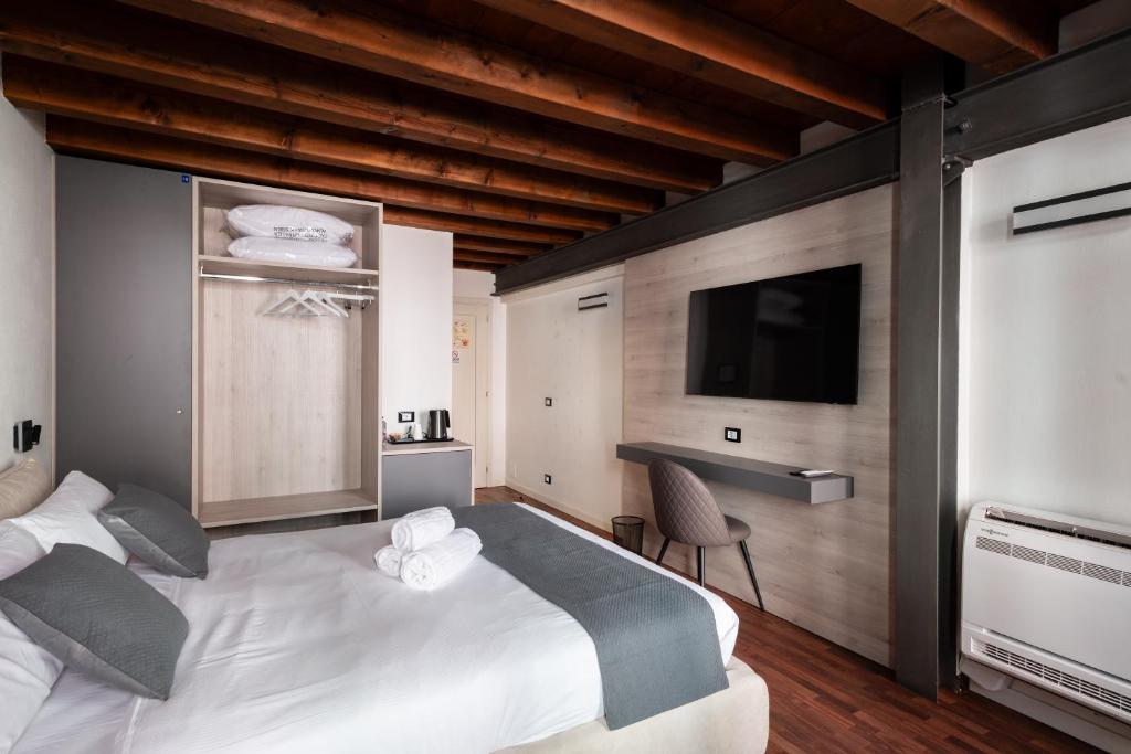 a bedroom with a large white bed and a flat screen tv at GuestHost - Santo 86 Luxury Rooms in Padova