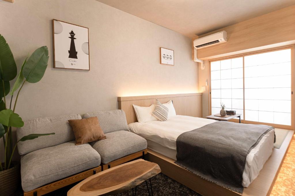 un dormitorio con una cama y un sofá en b&難波3号店, en Osaka