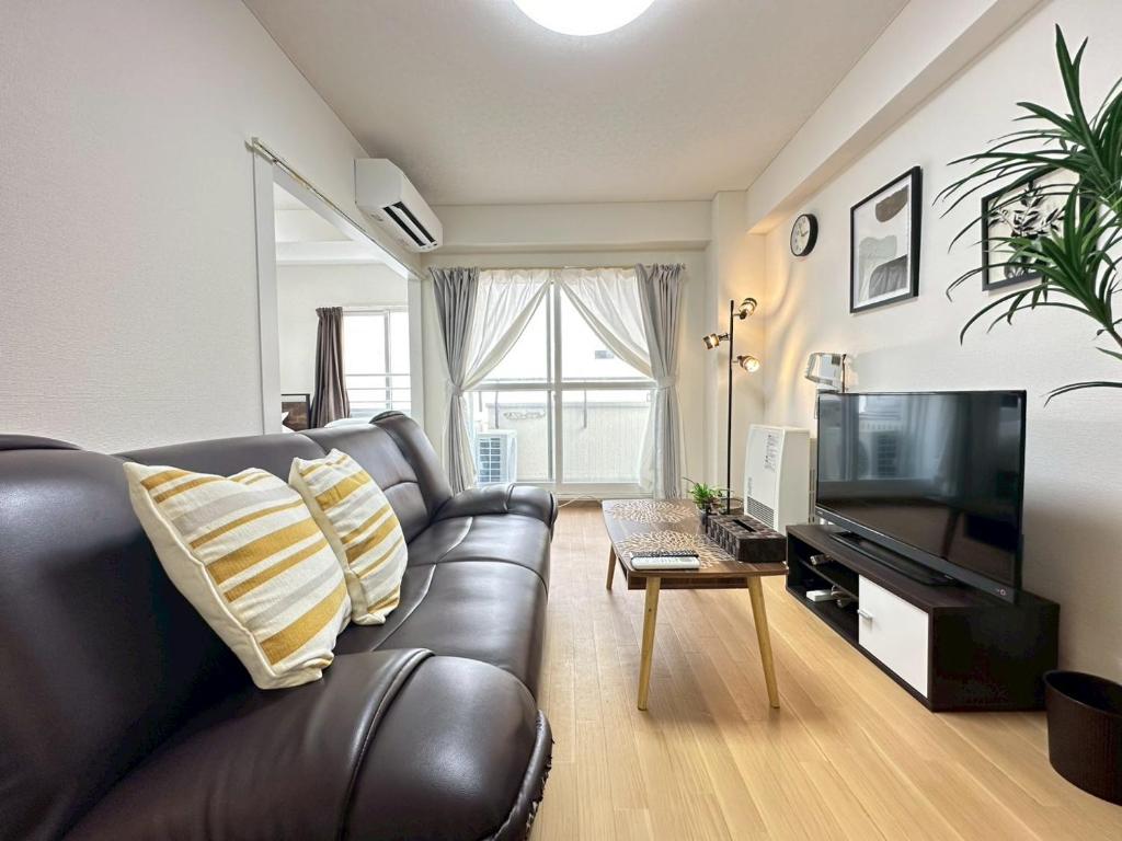 ein Wohnzimmer mit Ledercouch und Fernseher in der Unterkunft NewOpenSapporo TanukikojiShimaya Building403 in Sapporo