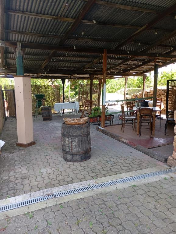 a covered patio with a table and chairs and a barrel at Rive rosse in Masserano