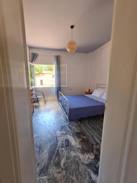a bedroom with a blue bed and a window at Modern traditional tranquil house with garden in Nea Makri