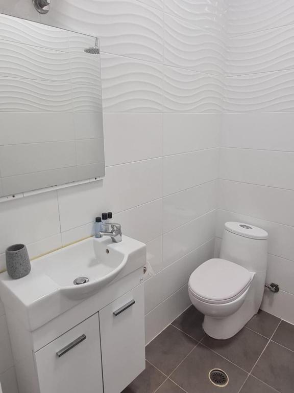 a white bathroom with a toilet and a sink at Modern traditional tranquil house with garden in Nea Makri