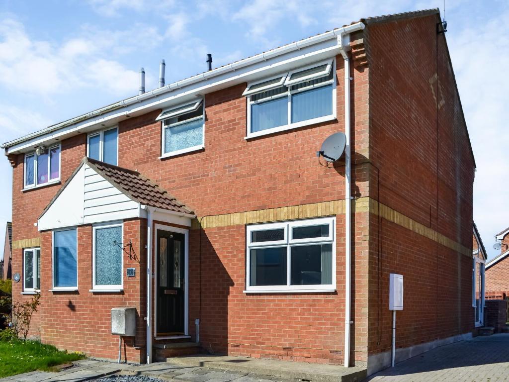 a red brick house with white windows on a street at Swan's Nest in Filey