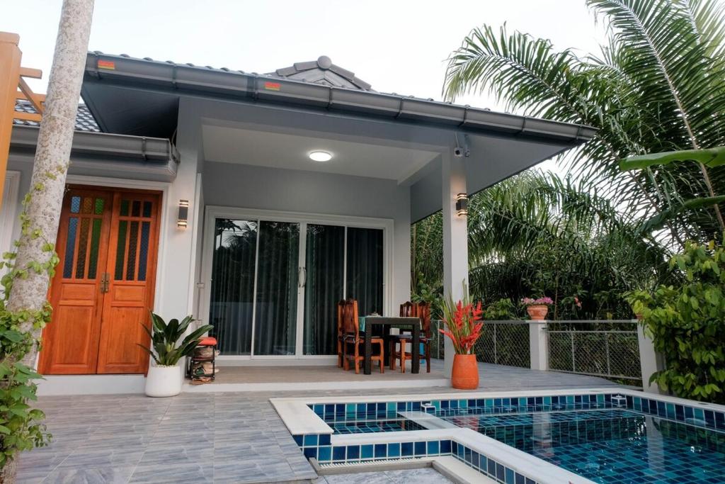 a house with a swimming pool in front of a house at Jampun Pool Villa in Klong Muang Beach