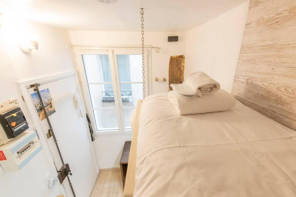 Cette chambre comprend un lit et une fenêtre. dans l'établissement Saint Denis - Studio cosy près de la place du Châtelet, à Paris