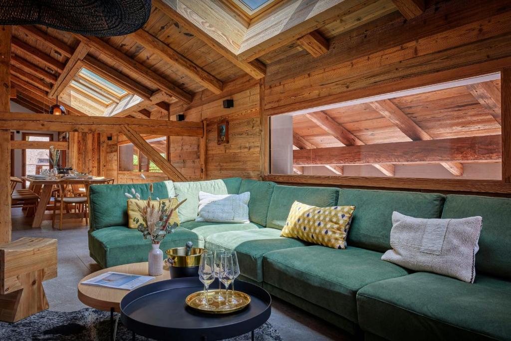 a living room with a green couch and a table at Chalet Plume - OVO Network in Morzine