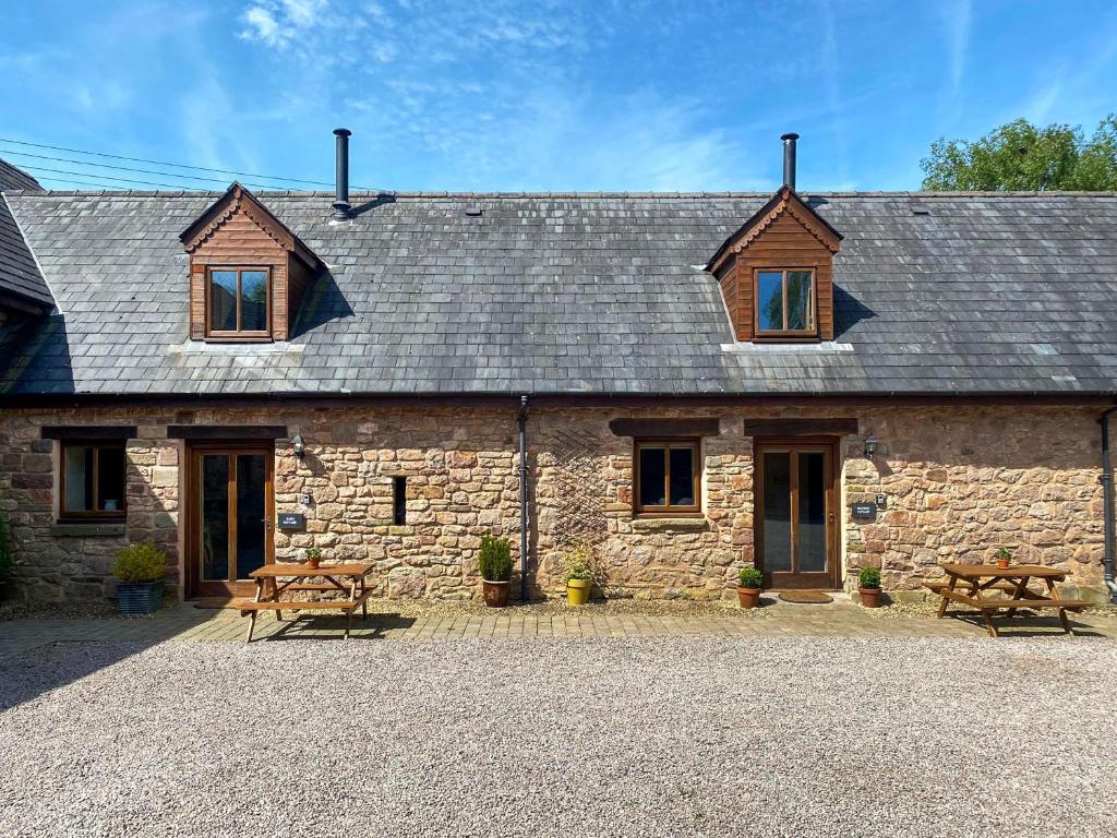 a stone house with two benches and two windows at Bramble Cottage in Newland