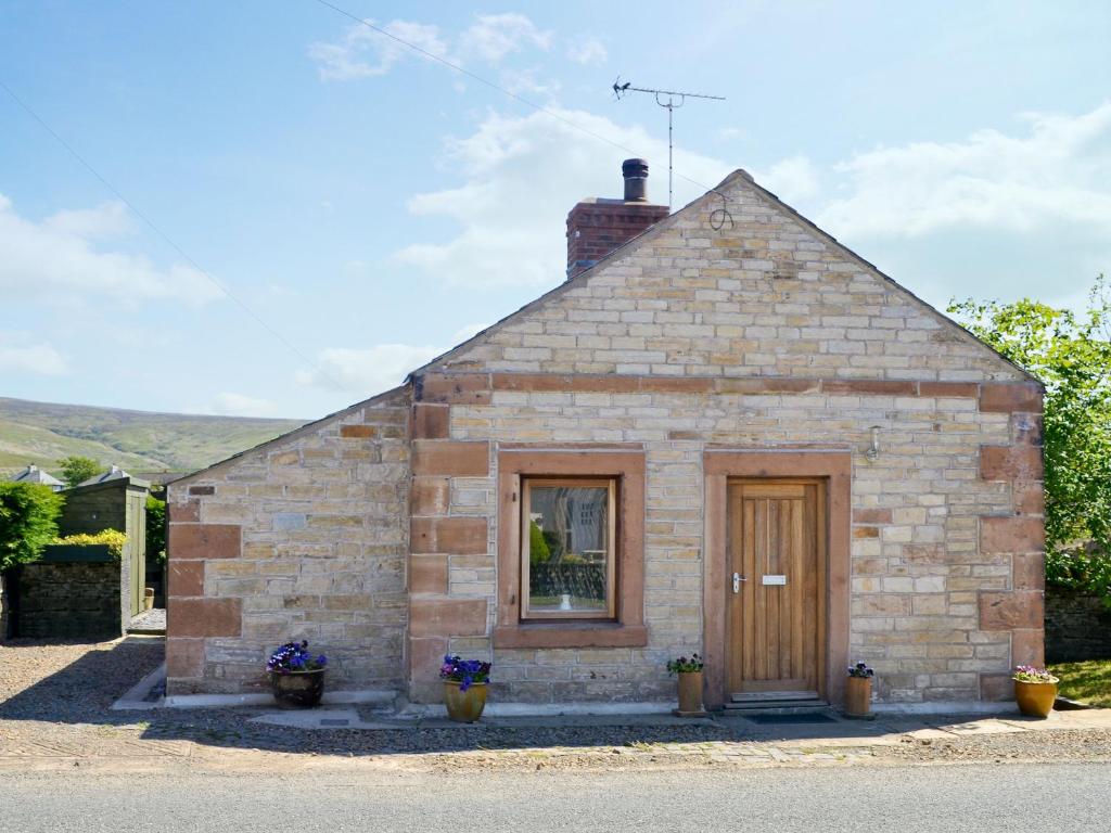 a small brick building with a window and a door at Blackhill Cottage in Farlam