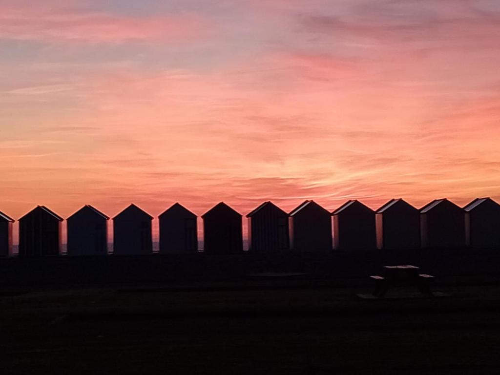 a fence with a sunset in the background at Le Nid Marin, Cayeux-sur-Mer, Baie de Somme in Cayeux-sur-Mer