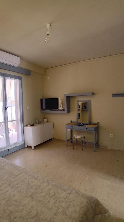 pusty pokój z biurkiem i telewizorem na ścianie w obiekcie Aggelika's Home w mieście Akrogiali