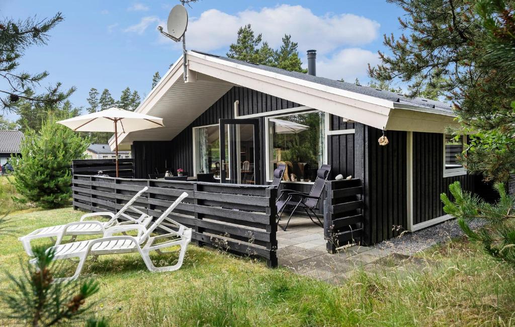 a black cottage with two chairs and an umbrella at Holiday Home Hedevej Xii Denmk in Ho