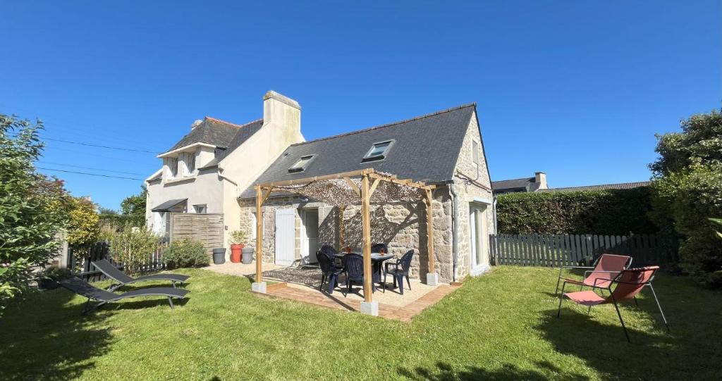 une cour avec une table et des chaises dans la cour dans l'établissement Maison rénovée 3 chambres pour 5 personnes, proche mer, parking, à Cléder