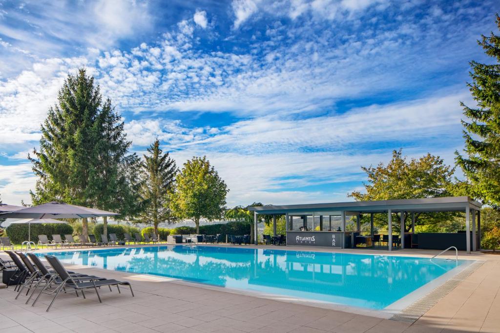 a swimming pool with chairs and a pavilion at Hotel Atlantis in Brno