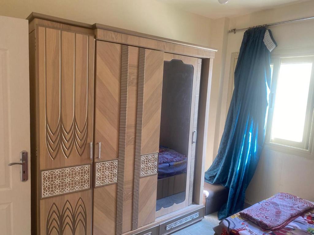 a large wooden cabinet in a bedroom with a window at استيلا هايتس الساحل الشمالي in Dawwār ‘Abd al Qādir Qāsim