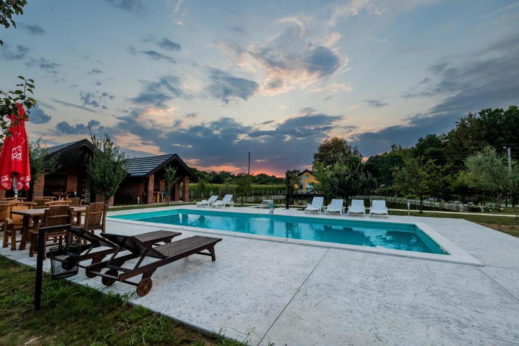 a swimming pool with a table and chairs next to it at Etno Camp Lucić in Odžak