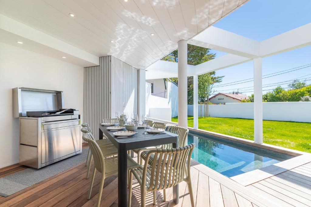 a dining room with a table and chairs next to a swimming pool at Villa Baroya - Villa piscine proche des plages in Bidart