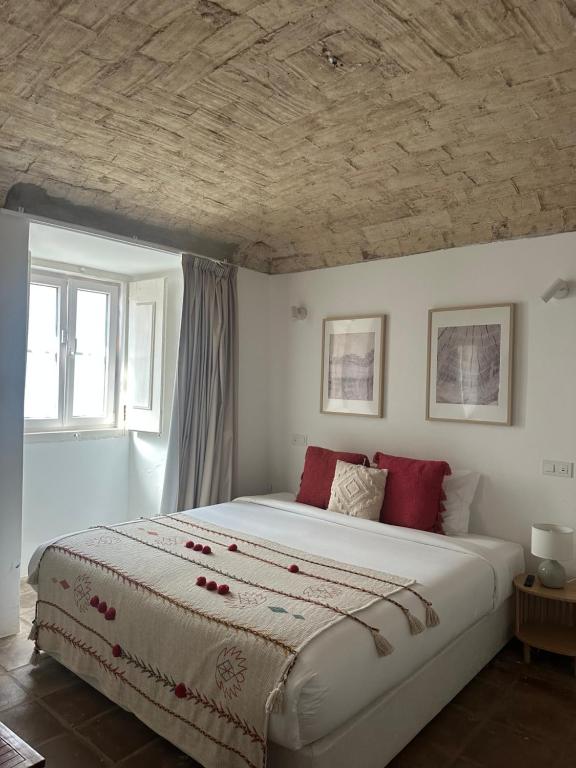 a bedroom with a large white bed with red pillows at Solar de Arrayollos by PURUS in Arraiolos