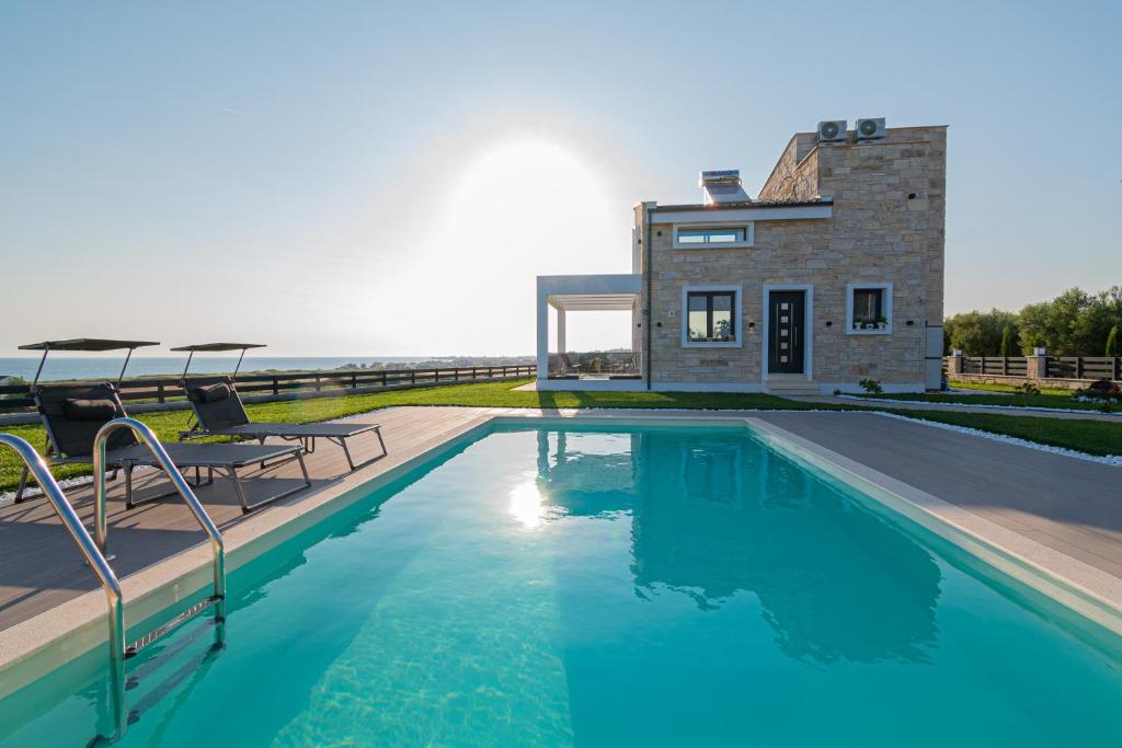 a house with a swimming pool next to the ocean at Villa Amelia by Travel Pro - Mouries Halkidiki in Paralia Dionysiou