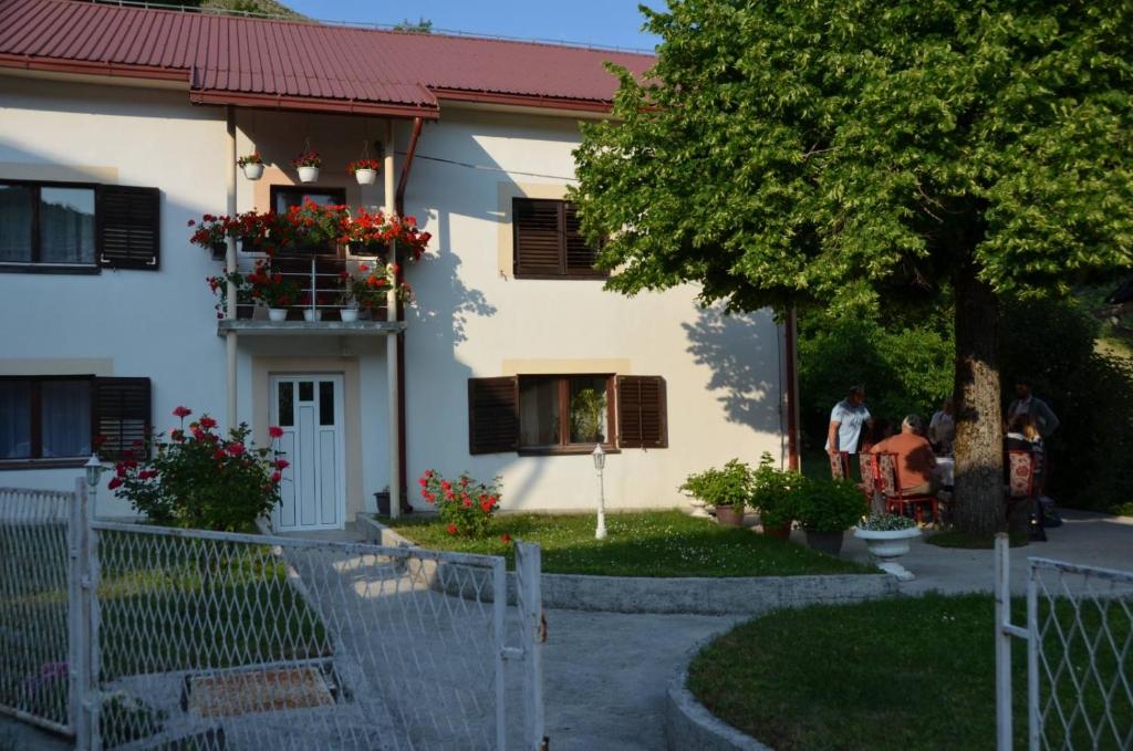 a house with a tree and people standing in front of it at Domaćinstvo Koprivica in Zapolje