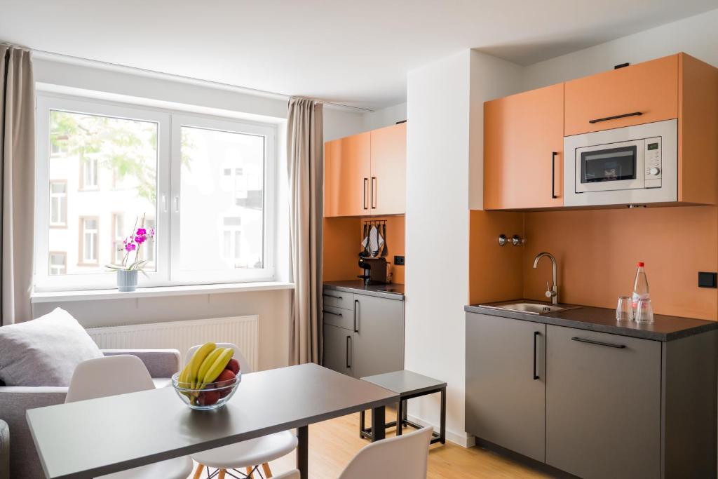a kitchen and a living room with a table at Homaris Apartments Nibelungen in Frankfurt/Main