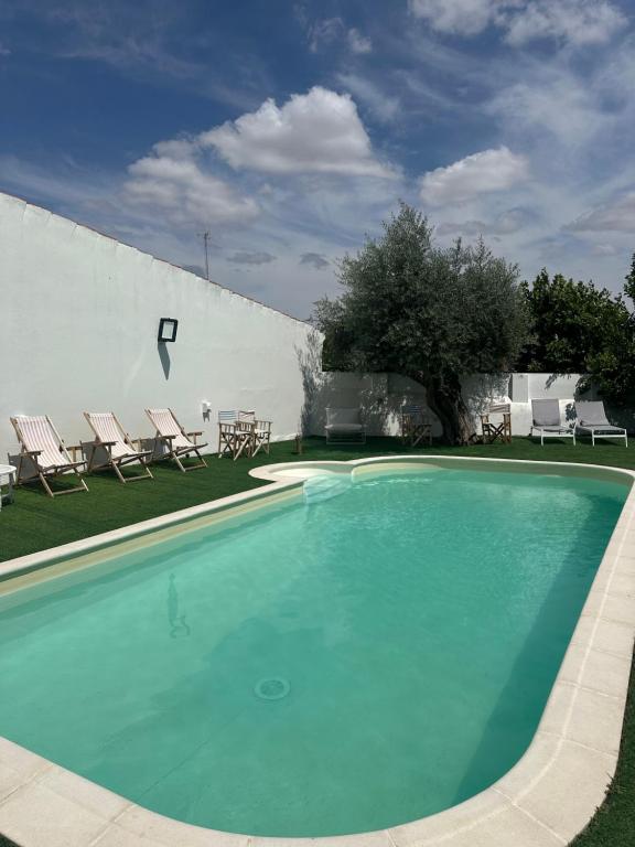 a swimming pool with chairs and a white wall at Solar de Arrayollos by PURUS in Arraiolos