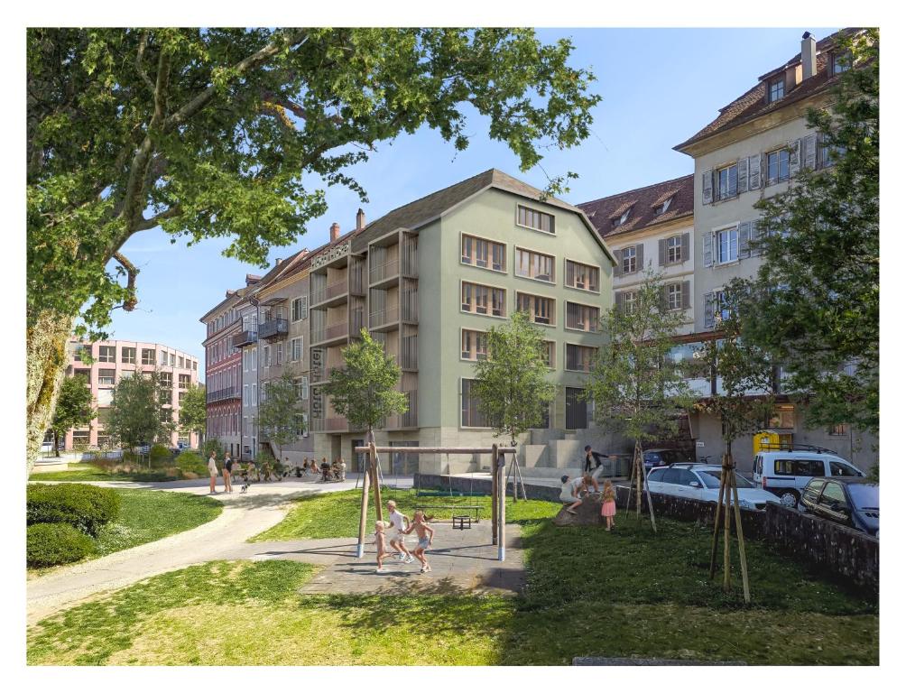 a group of children playing in a park in front of a building at Hota Hotel Porrentruy in Porrentruy