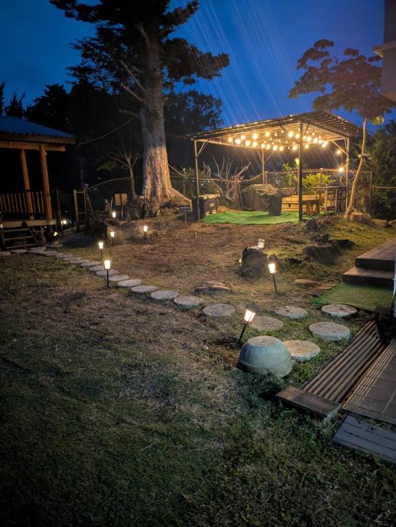 a garden at night with lights on the grass at niko villa 伊豆高原Woody棟 in Ito