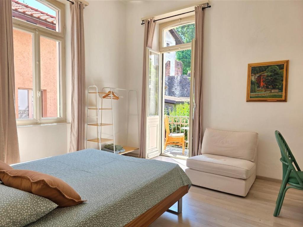 a bedroom with a bed and a chair and a window at Palacinema Apartment - Locarno Old Town in Locarno