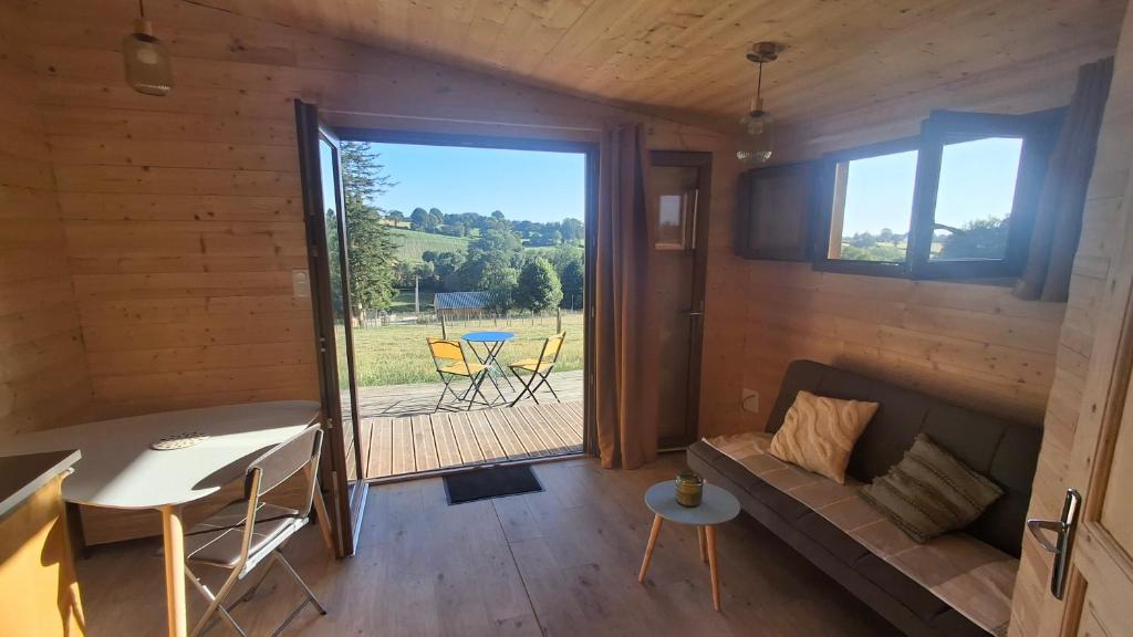 a living room with a couch and a table and a patio at La ferme de beau soleil Gîte et cabanes in Saint-Gilles-du-Mené