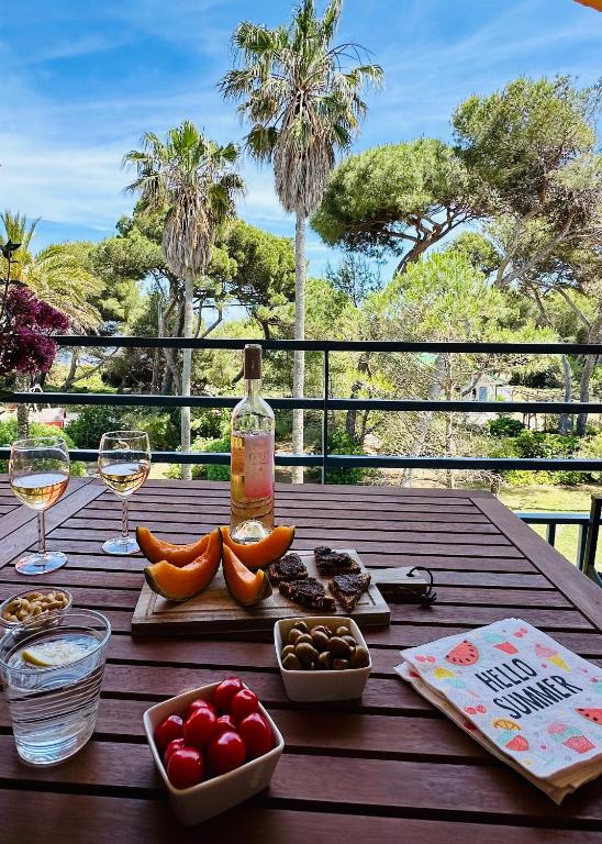 - une table en bois avec une bouteille de vin et de la nourriture dans l'établissement PINEDE PLAGE VUE MER Clim Jacuzzi, à Hyères