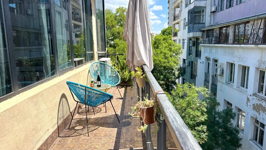 un balcón con 2 sillas y una sombrilla en un edificio en Cloudy Tbilisi Apartment, en Tiflis