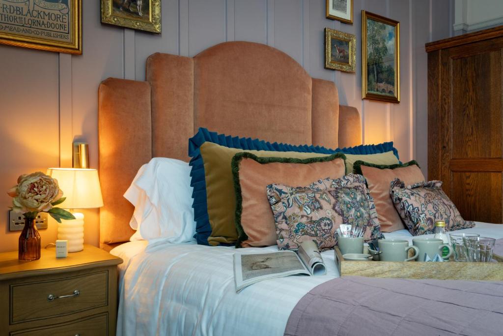 ein Bett mit Kissen und ein Buch darauf in der Unterkunft The Ragged Robin - A Heartwood Inn in Godalming