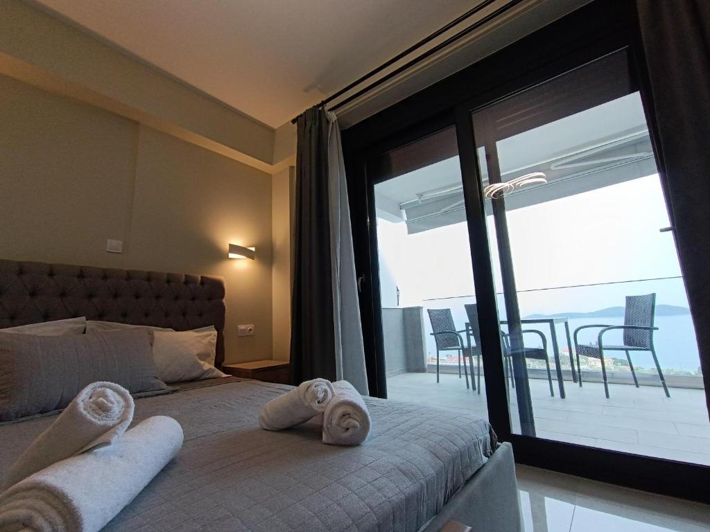 a bedroom with a bed and a large window with a balcony at ALTA MARE in Nea Peramos