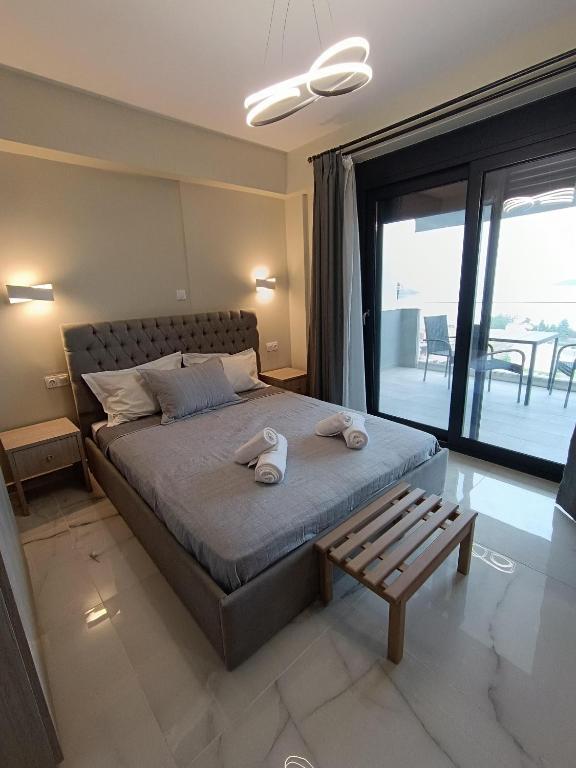 a bedroom with a bed with a bench and a balcony at ALTA MARE in Nea Peramos