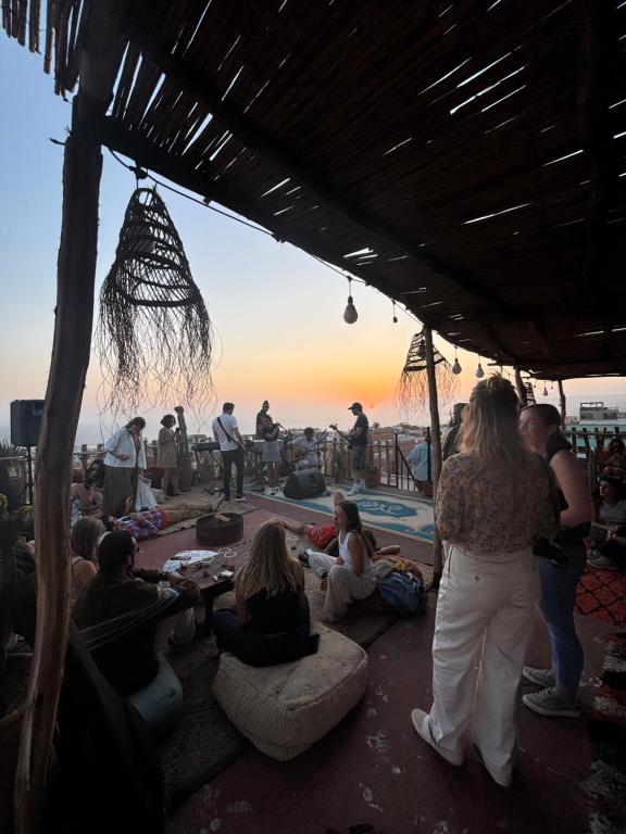 a group of people sitting on the ground watching the sunset at Berber Waves Surf House in Tamraght Ouzdar