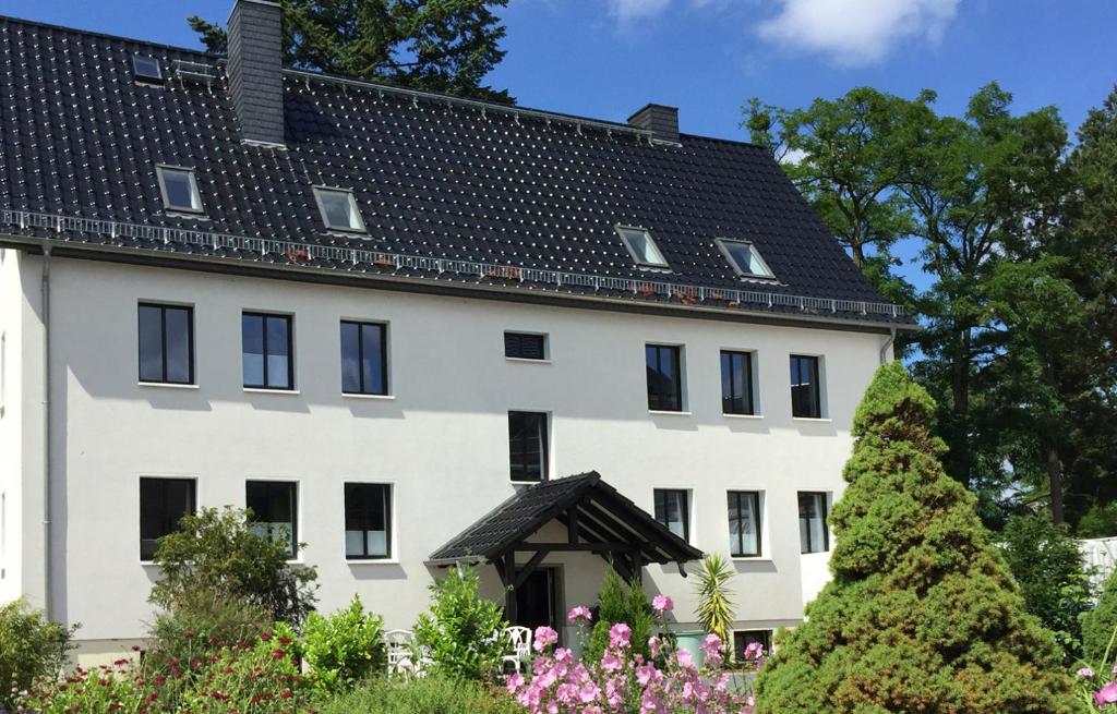 a large white building with a black roof at Haus am Röblinsee - Ferienwohnungen in Fürstenberg in Fürstenberg-Havel