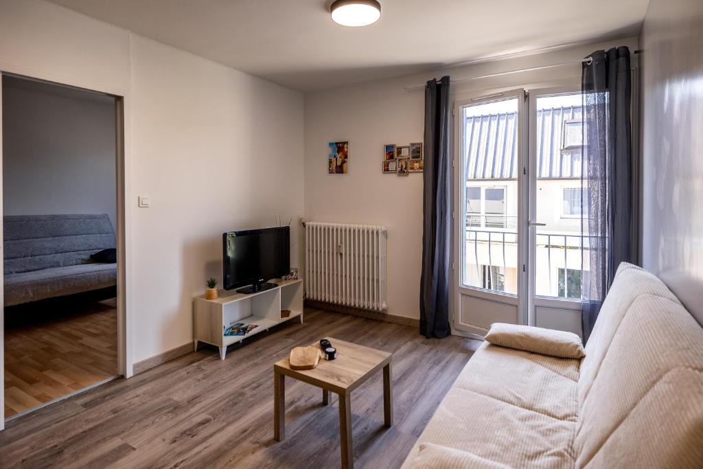 a living room with a couch and a tv at Appartement paisible au bord de l Isle avec parking in Périgueux