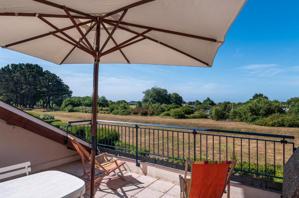 a patio with an umbrella and chairs on a balcony at Appartement Arzon in Arzon