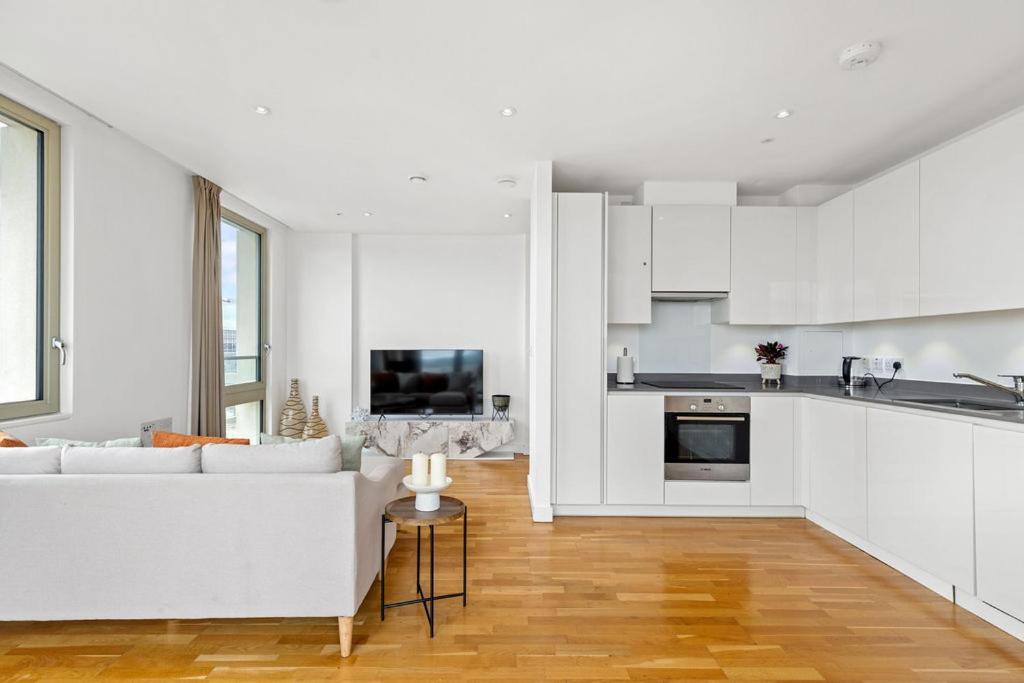 a white living room with a white couch and a kitchen at Luxury Penthouse Stratford City in London