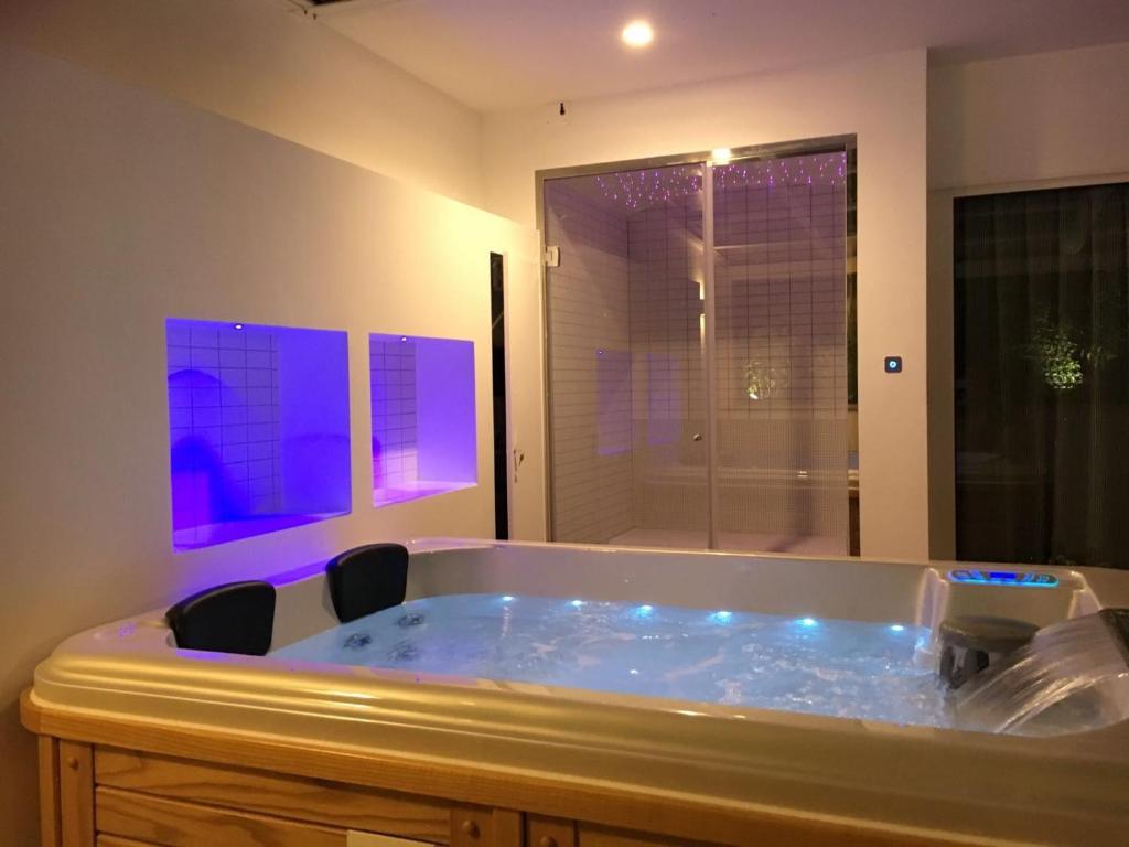 La salle de bains est pourvue d'une grande baignoire et de lumières violettes. dans l'établissement Principe Relais Suite & Spa, à Gravina in Puglia