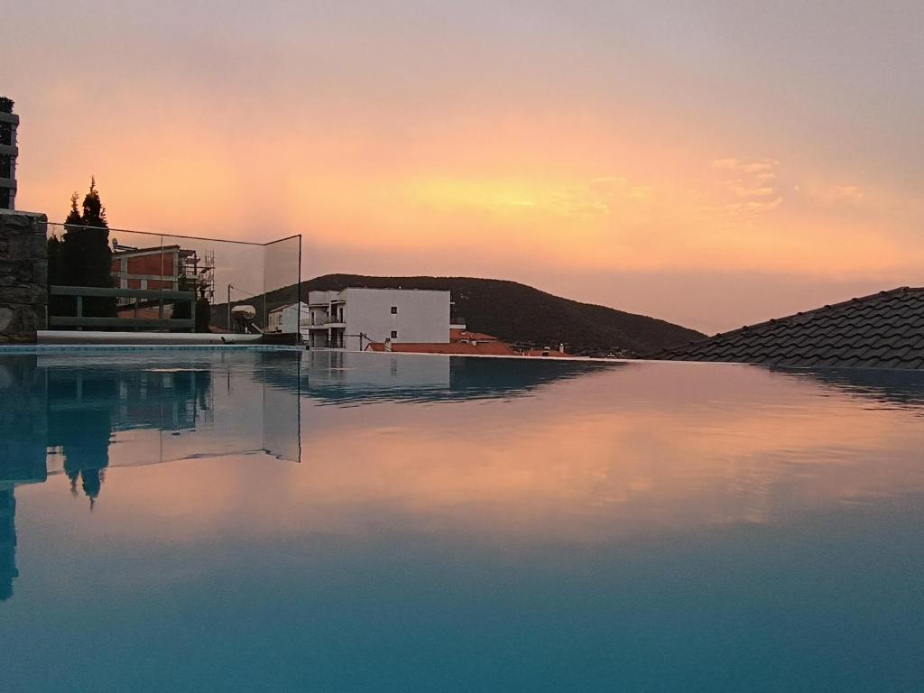 a pool of water with a sunset in the background at ALTA MARE in Nea Peramos
