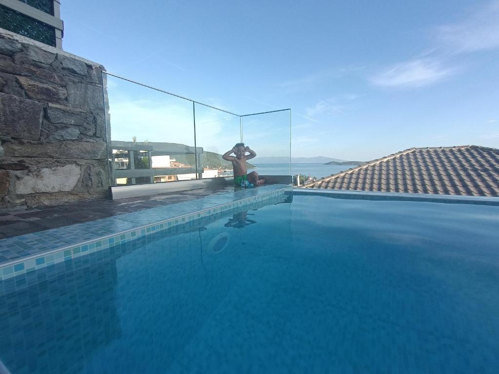 a man is standing next to a swimming pool at ALTA MARE in Nea Peramos