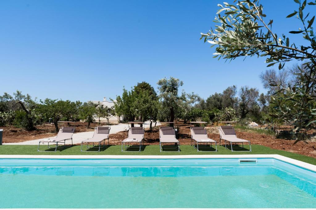 un groupe de chaises longues et une piscine dans l'établissement Meraki house con piscina privata, à San Michele Salentino